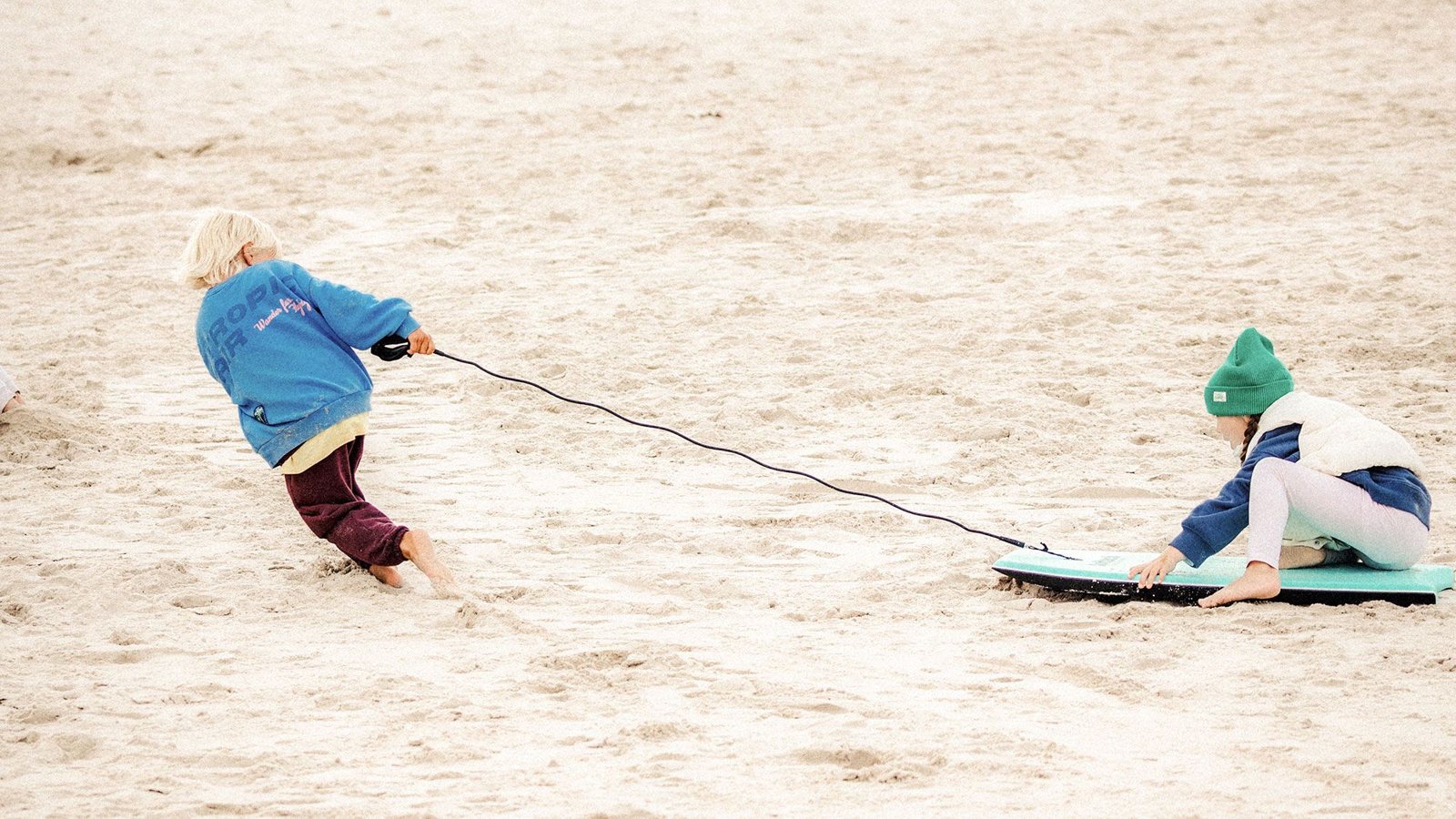 Dzieci bawią się bodyboardem z leashem na plaży